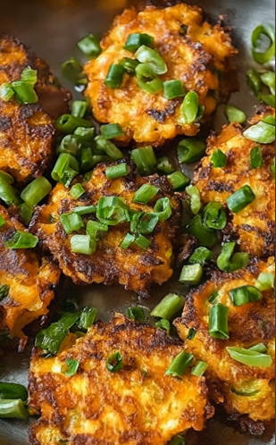 A plate of golden-brown carrot fritters garnished with green onions.